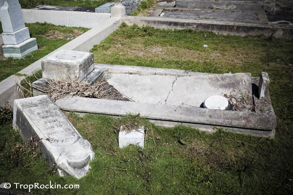 A tomb that has fallen inwards and a large grave stone fallen on to its side.