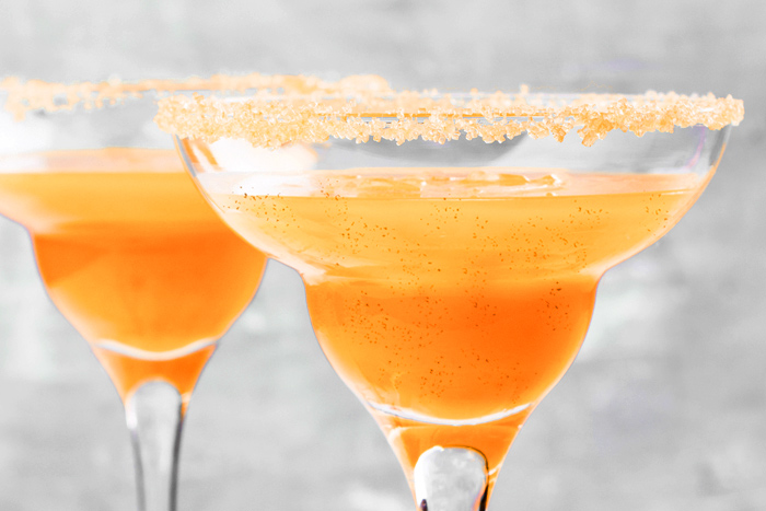Two Pumpkin Spice Margarita drinks in traditional margarita glasses with a gray background