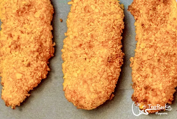 Up close look at these Corn Flakes chicken fingers cooked and displayed on baking sheet.