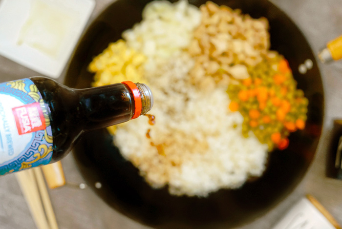 Pouring Soy Sauce over Fried Rice Ingredients in Pan