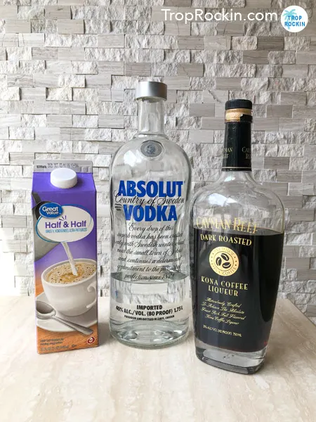 White Russian Ingredients: Bottle of Vodka, Coffee Liqueur and a carton of Half and Half on table.