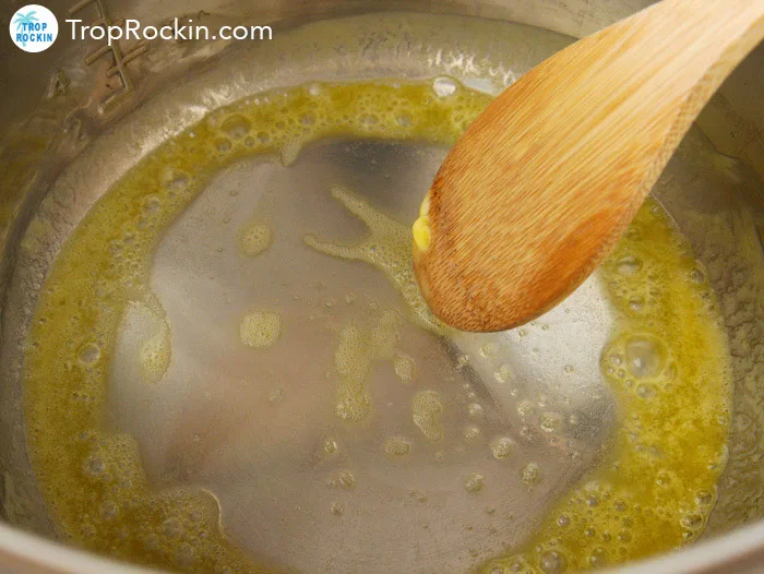 Melting butter inside instant pot stirring with wooden spoon.