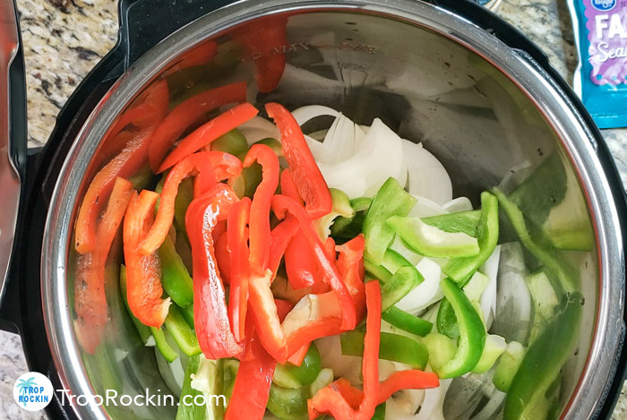 Sliced raw bell peppers, red peppers and onions in an instant pot.