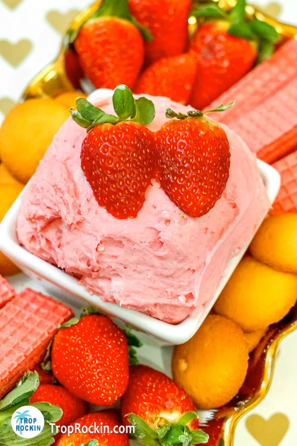 Strawberry Cream Cheese Fruit Dip topped with two fresh strawberries in a bowl with platter of cookies underneath.