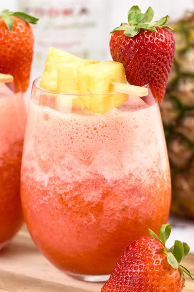 Pineapple Strawberry slush drink with pineapple chunks and fresh strawberries for garnish.