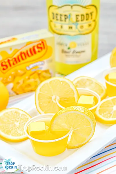 Yellow Starburst Jello Shots on plate with Deep Eddy Lemon Vodka and Starburst Jello box in background.