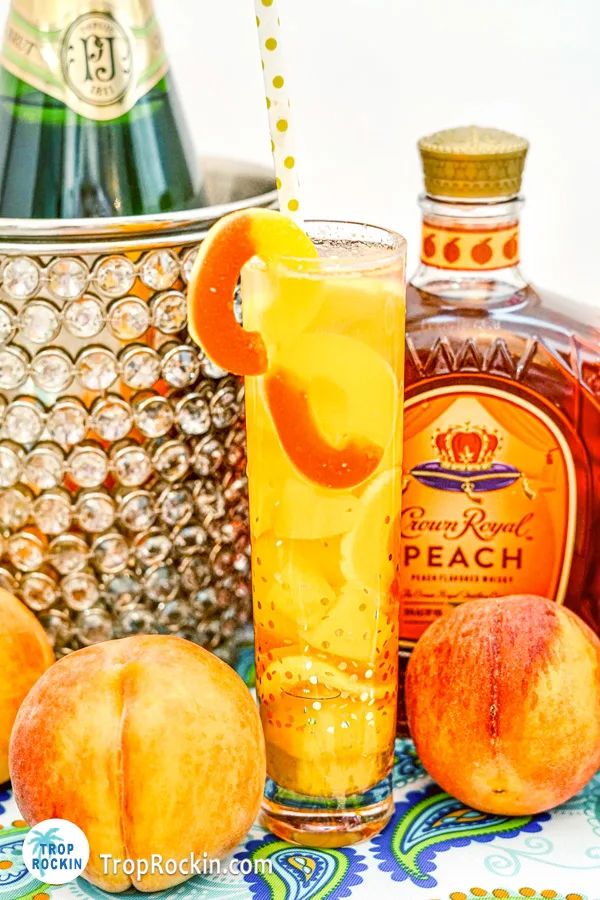 Crown Peach drink with peach rings and bottle of crown peach and champagne in background.