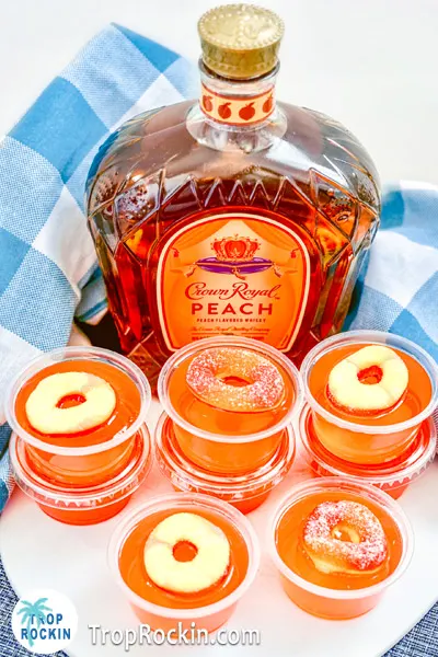 Pretty Crown Peach Jello Shots and a bottle of Crown Royal Peach bottle with a blue checkered table cloth.