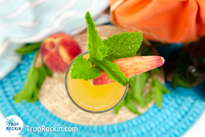 Top view of a Crown Peach Mimosa with peach slice and mint sprig for garnishes.