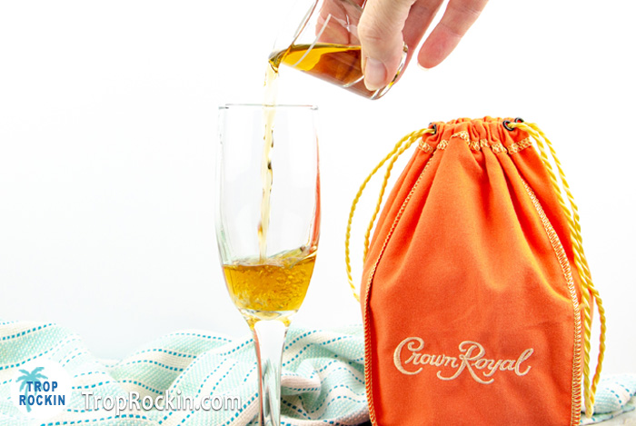 Pouring Crown Peach whisky into champagne glass.