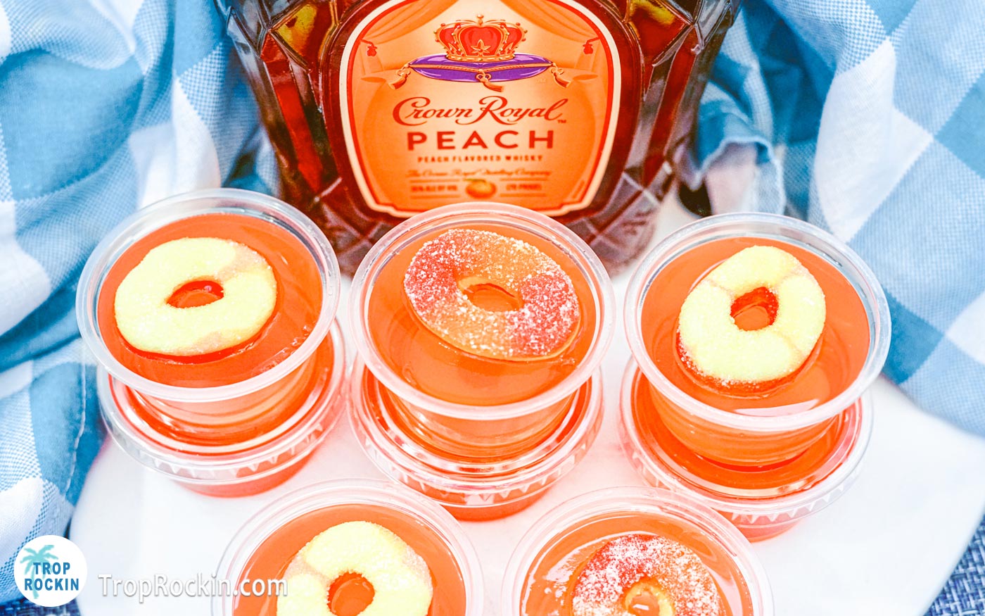 Crown peach jello shots with peach rings for garnish on top with a bottle of Crown Royal Peach Whisky in the background.