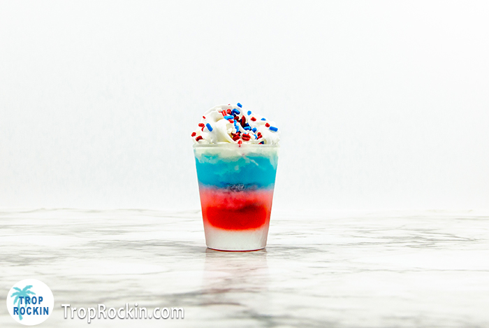 Red Whtie and Blue layred shot with whipped cream and patriotic sprinkles on marble counter top. 