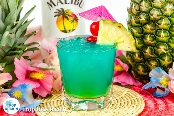 Electric Smurf Drink with garnish, Malibu Rum bottle and a pineapple in the background.