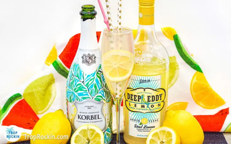 Deep Eddy's Lemon Vodka bottle, Champagne bottle and Vodka Lemonade Drink with lemon slice for garnish.
