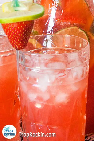 Tropical Drink Strawberry rum punch drink with fresh strawberry and limes for garnish.