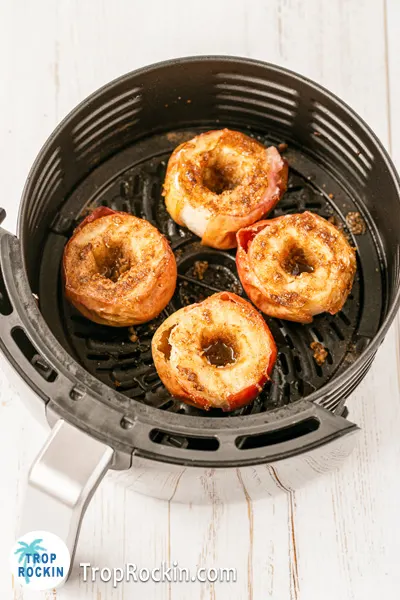 Four cooked apples in the air fryer basket.