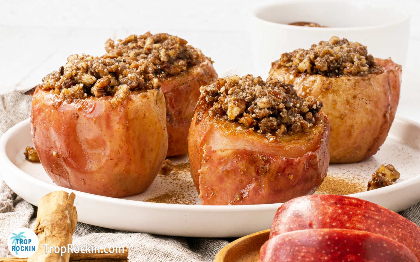 Four air fryer baked apples with cinnamon pecans stuffing on a plate. 