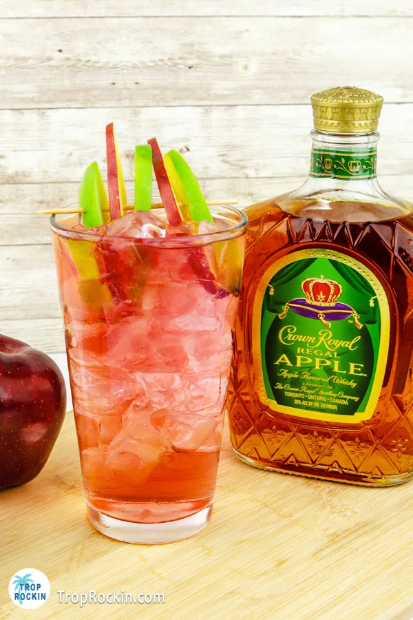 Crown Apple Drink with fresh apple slices for garnish on cutting board with a bottle of Crown Apple whisky.