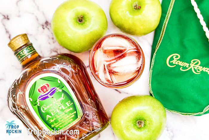 Top view of Crown Apple and Cranberry drink with Crown Apple bottle, green crown apple bag and fresh green apples.
