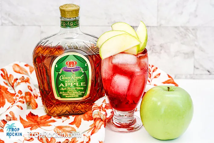 Crown Apple and Cranberry drink with a bottle o Crown Apple and sliced green apples for garnish.