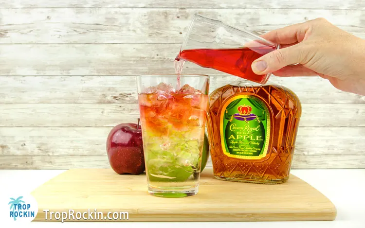 Pouring cranberry juice into the cocktail glass with ice, sprite and Crown Apple.