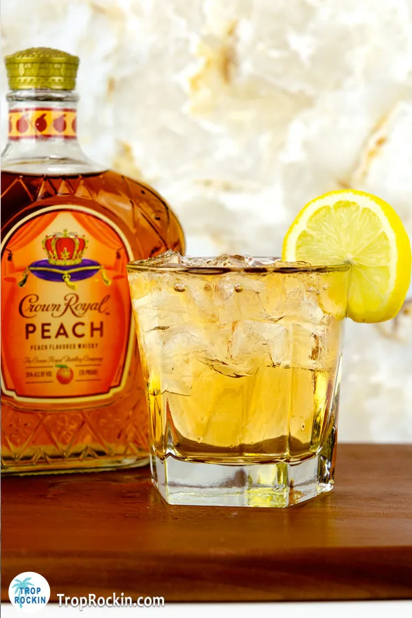 Crown Royal Peach and Sprite drink with ice and lemon garnish with Crown Royal Peach bottle.