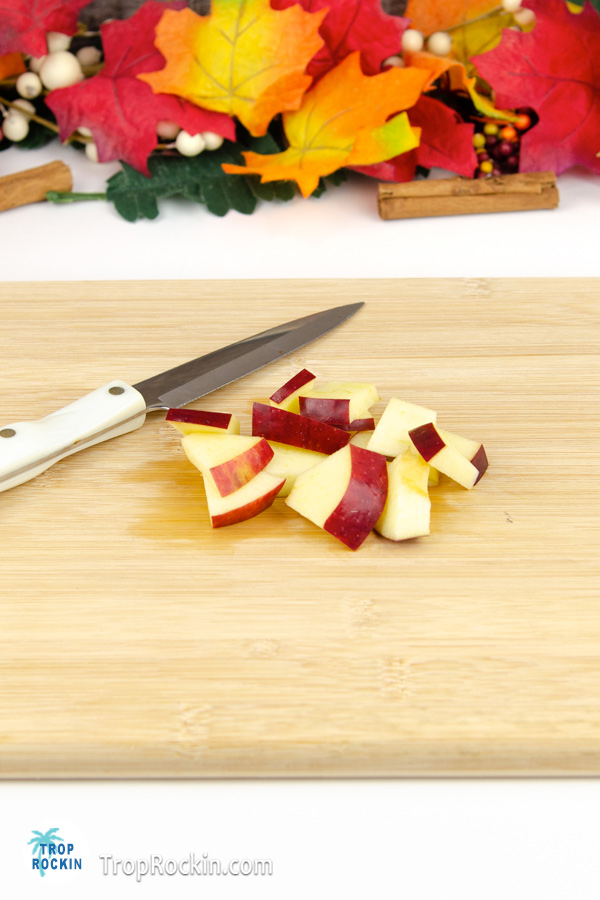 Chopped apple chunks with knife on a cutting board.