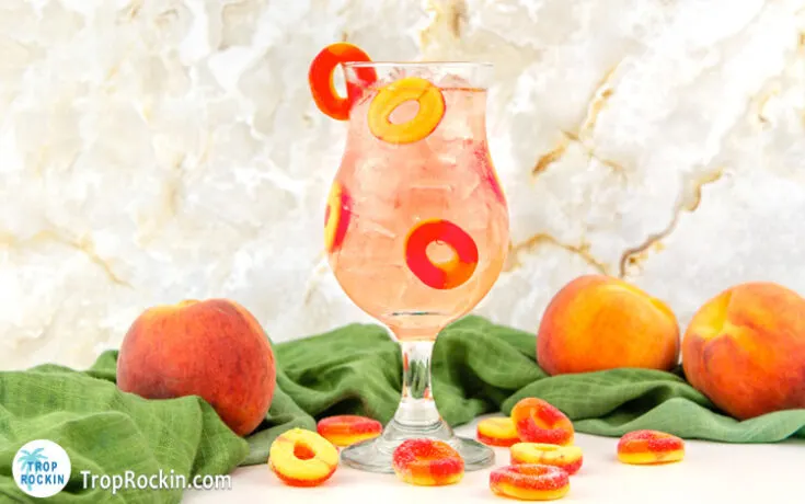 Crown Royal Peach Ring Drink in a hurricane glass with peach rings for garnish.
