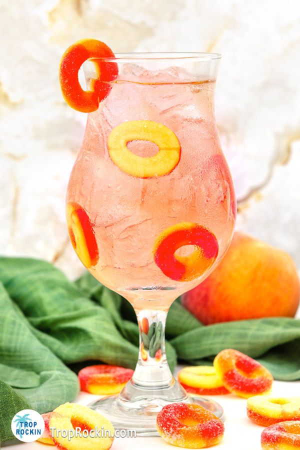 Up close Crown Royal Peach Ring Drink in a hurricane glass with peach rings for garnish.