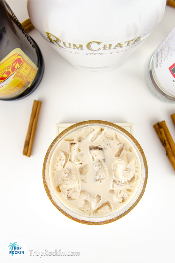 Top view of a Rumchata White Russian with liqor bottles in background.