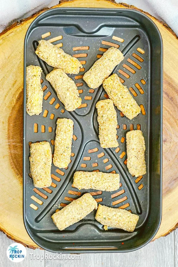 Arranging mozzarella sticks in air fryer basket in a single layer.