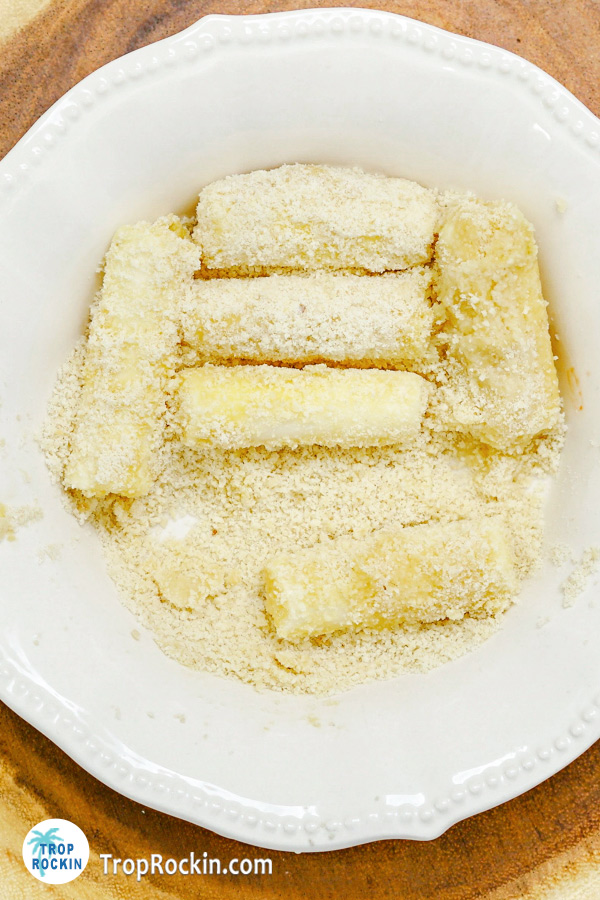 Coating the egg washed cheese sticks in flour.