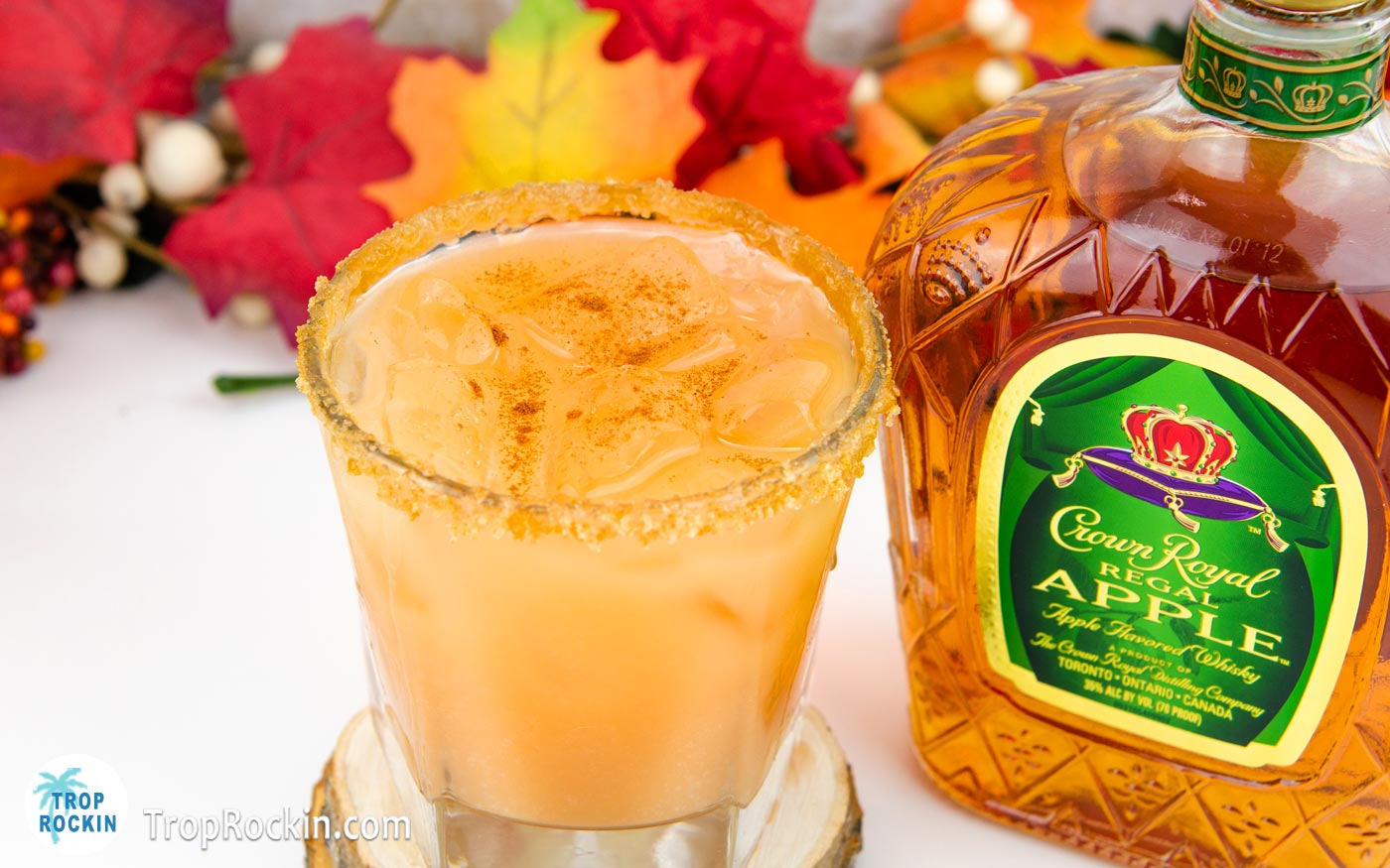 Crown Royal Caramel Apple drink with brown sugar and caramel rim next to a bottle of Crown Royal Apple Whisky.