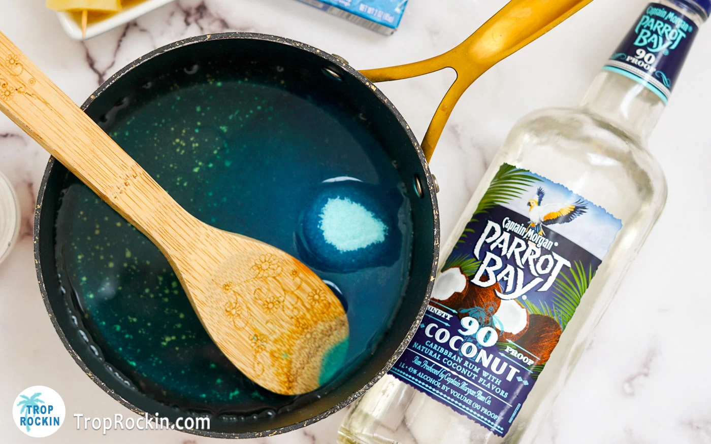 Mixing blue jello with wooden spoon in hot water in a pot.
