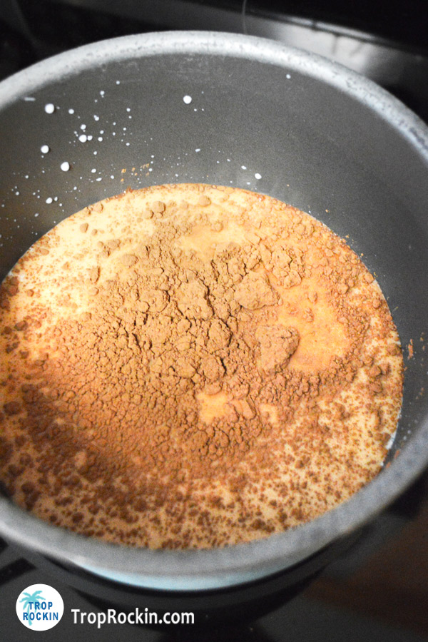 Milke and cocoa powder in a pot on the stove.