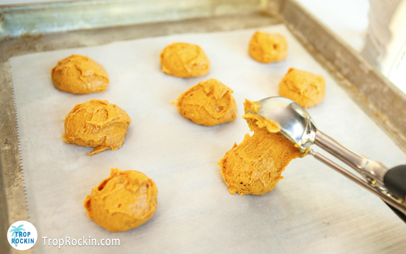 Using a cookie scoop to Drop dough on baking sheet covered with parchment paper.