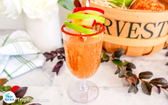 Caramel Apple Mimosa with apple slices for garnish and red sugar rim.