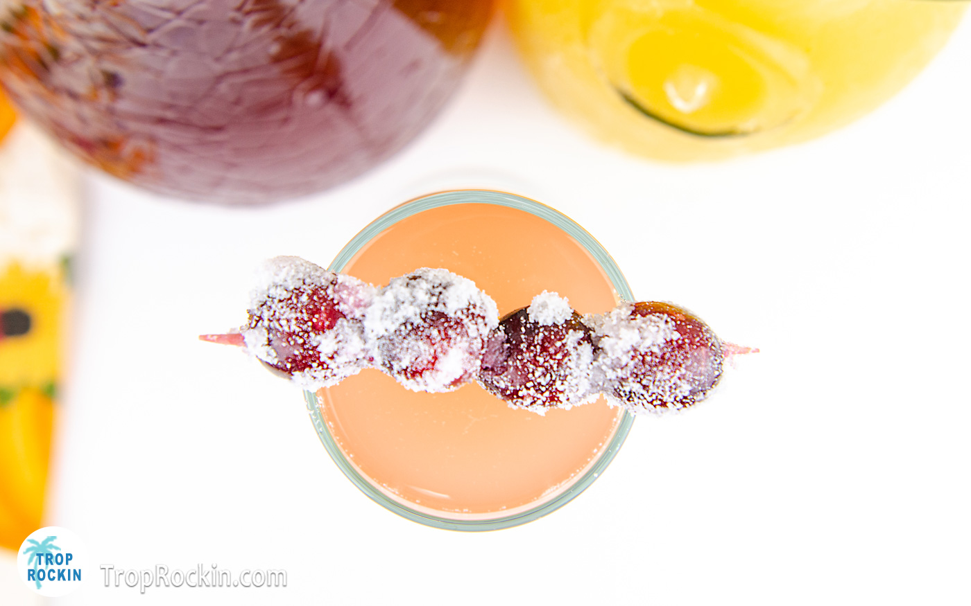 Top view of the cranberry orange mimosa with the skewer of sugar coated cranberries place across the top of the chapagne flute.