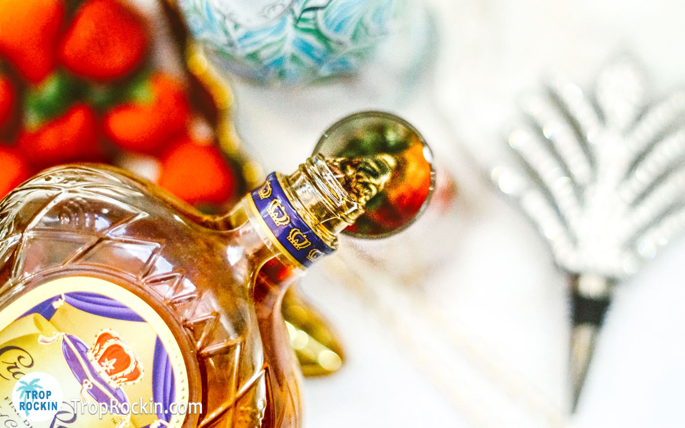 Pouring crown royal whiskey into glass over strawberries.