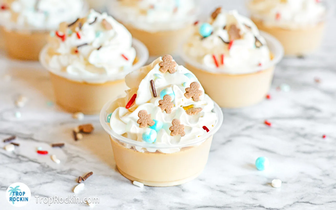 Gingerbread Jello Shots with whipped cream displayed on counter top.