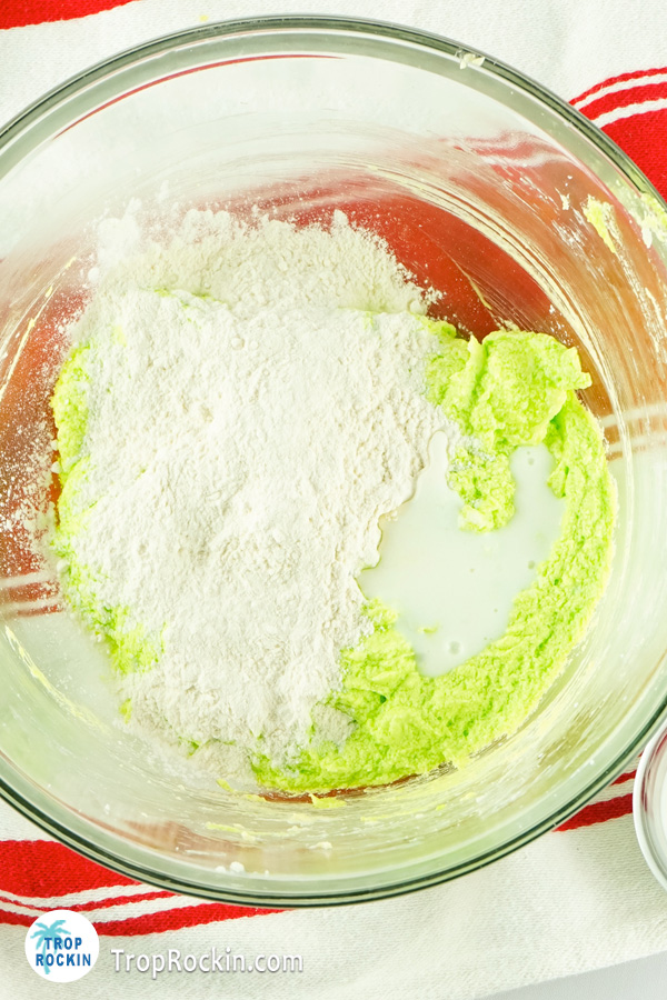 Adding flour and milk to grinch cupcake batter.