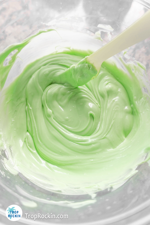 Melted green candy melts in a clear mixing bowl.