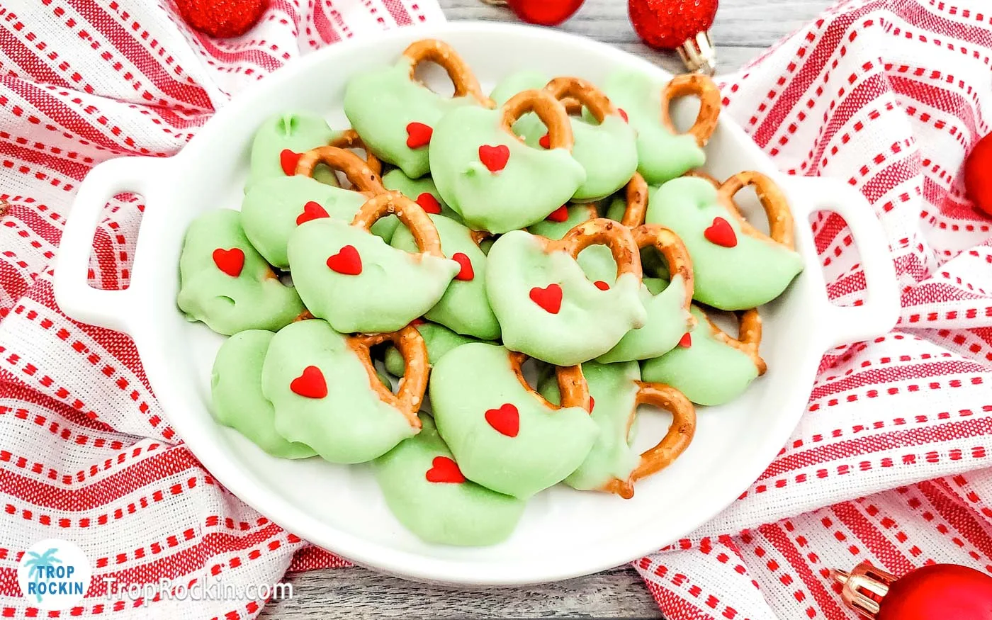 Grinch pretzels stacked on a white plate.