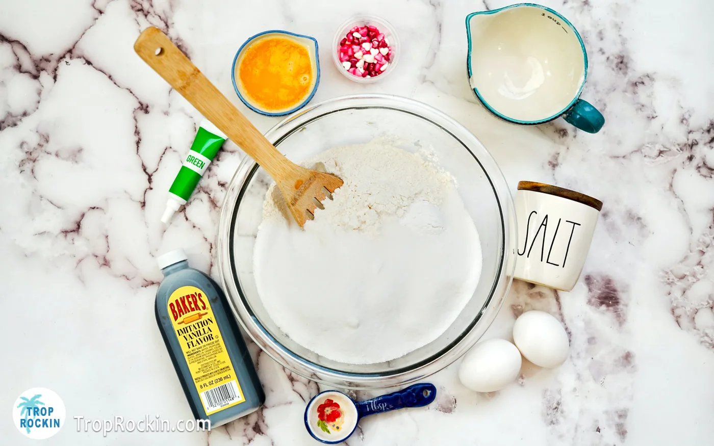 All cookie dough dry ingredients in a large mixing bowl with a wooden spoon.