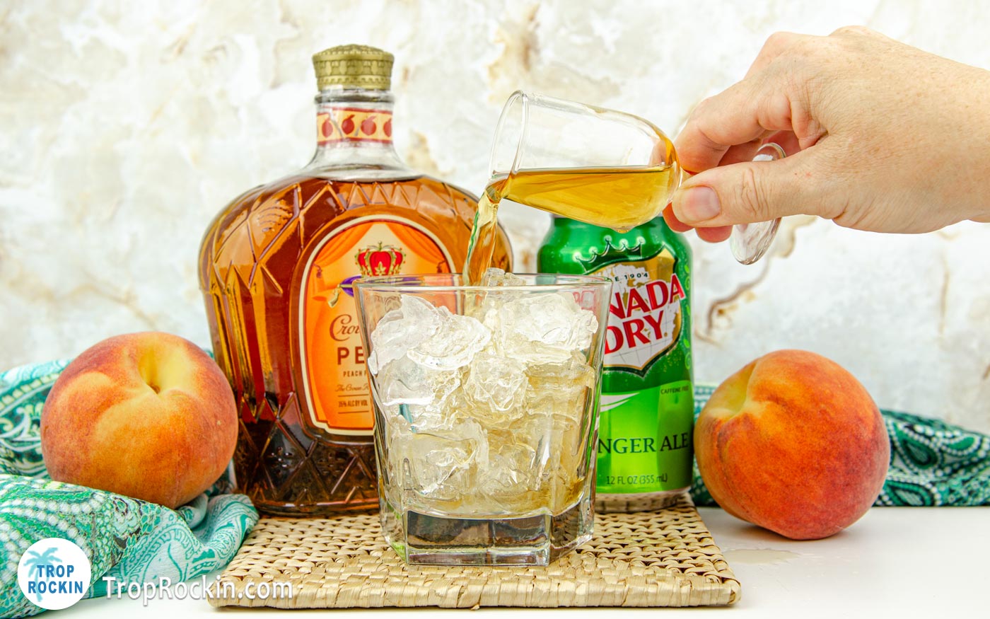 Pouring crown royal peach whisky into cocktail glass filled with ice.