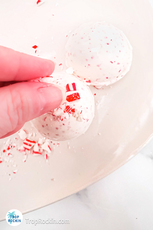 Dropping a pinch of crushed candy canes on top of the hot chocolate bomb to stick to the warm candy squeezed on top.