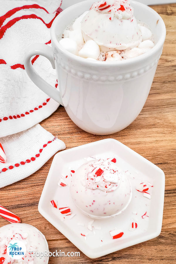 Peppermint hot chocolate bomb on a saucer and one in a cup of milk.