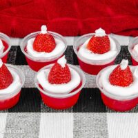 Santa hat jello shots lined up on a black and white place mat.