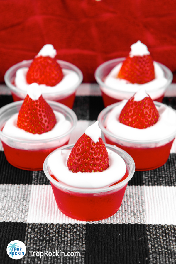 Five Santa Hat Jello shots on a black and white placemat.
