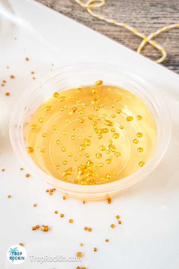 Upclose look at a chapagne jello shot with gold sprinkles.
